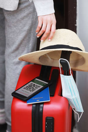 New normal concept. woman ready to travel with smartphone with an immune digital health passport. female with protective mask, straw hat and passport is traveling by plane during a pandemicの写真素材