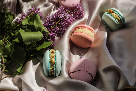 pink and mint french macaroons or macarons cookies and a lilac flowers on a cloth background....