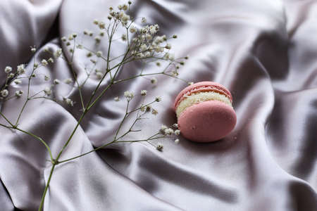 pink french macaroons or macarons cookies and a white flowers on a cloth background. Natural fruit and berry flavors, creamy stuffing for valentines mother day easter with love foodの写真素材