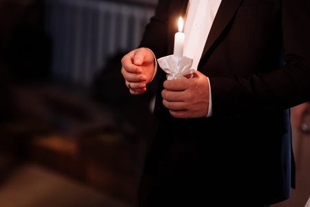 Couple in church. groom hold shiny candles during the ceremony in church. Hands of newlywed with...