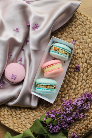 pink and mint french macaroons or macarons cookies in gift box and a lilac flowers on a cloth and...