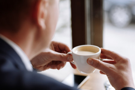 A man in a business suit holds a cup of hot coffee in his hands. Morning businessman in cafe .Copy space.の写真素材