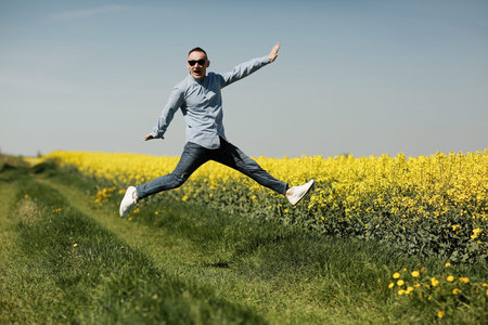 handsome young man in black sweatshirt and white short, in summer field outdoor, having fun on hay...