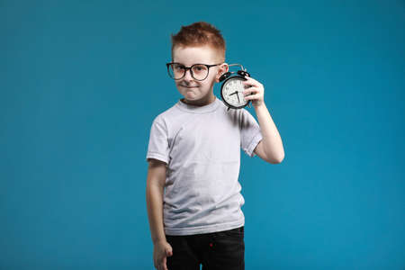 Little boy taking a picture using a retro camera and with finger pointed up. Child boy with vintage photo camera isolated on blue background. Old technology concept. Child learning photography.の写真素材