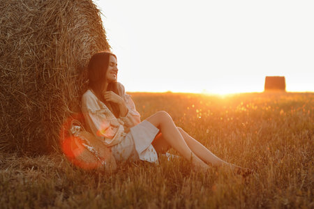 silhouette of a romantic young woman on a swing over lake at sunset. Young girl traveler sitting on...