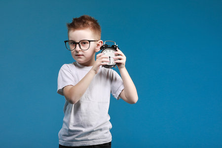 schoolboy in glasses closing laptop sitting on bed. Child doing school homework and tired looking on...