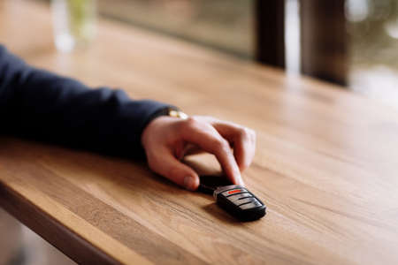 Close view of car keys put on the table by rich suited businessman in the cafe. coffee break in cafe or restaurantの写真素材