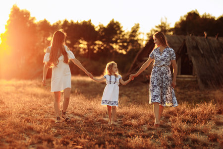 Two young mothers are walking outdoors in summer on sunset with her baby. LGBT Lesbian Couple. The concept of family and healthy lifestyle.の写真素材