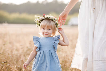 Young mother walking with her little daughter in the gold field. Family holiday in garden, park. Portrait mom with child together on nature. Mum, little daughter outdoors. Happy Mothers Day. Close up.の写真素材
