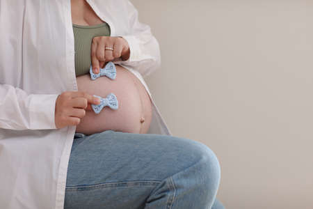 close up hands on pregnant mother holding baby clothes, two blue bows. Lover woman waiting child. Preparation for childbirth, Girl big belly advanced pregnancy. selective focusの写真素材