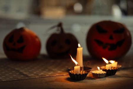 candles are burning on the table. Halloween pumpkin lantern with scary face on background. Family preparing all hallows eve Halloween party decorations. Background, copy space. selective focus.の写真素材