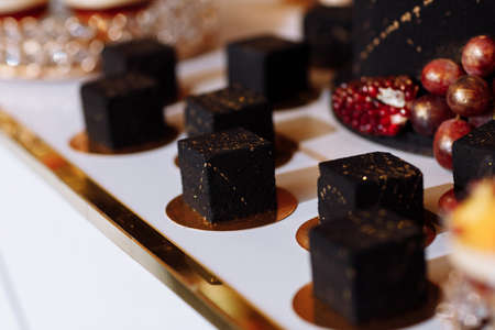 French mousse cake covered with dark chocolate icing. Modern European dessert decorated with gold. selective focus.の写真素材