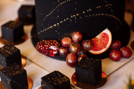 French mousse cake covered with dark chocolate icing. Modern European dessert decorated with gold. selective focus.の写真素材