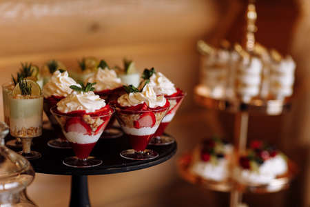 luxury wedding catering, table with modern desserts, cupcakes, sweets with fruits. delicious candy bar at expensive wedding reception. party holiday celebration. selective focus.の写真素材