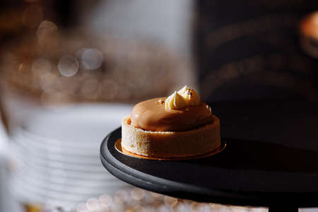 dough tartlet nuts with caramel on black tray, small round tartlet with a variety of fillings, crispy tartlet with hazelnuts, peanuts and other ingredients. selective focusの写真素材