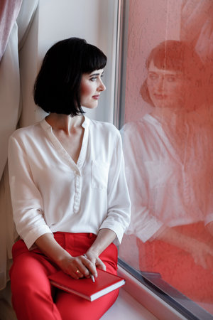 portrait of young European businesswoman with notebook is sitting by the window. Concept of...