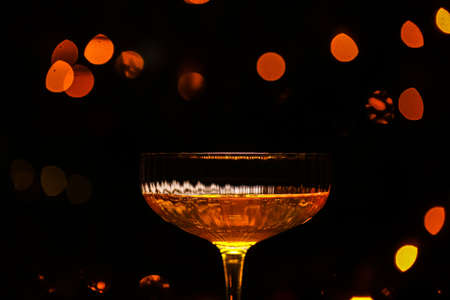 Beautiful glass of champagne against bokeh lights background with a decorated Christmas tree. Happy New Year 2022. Christmas and New Year holidays background, winter seasonの写真素材