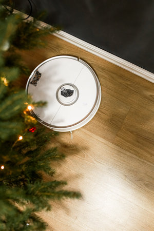 Smart home. Robot vacuum cleaner performs automatic cleaning. Cleans the parquet from Christmas tree...