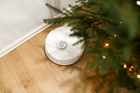 Smart home. Robot vacuum cleaner performs automatic cleaning. Cleans the parquet from Christmas tree...