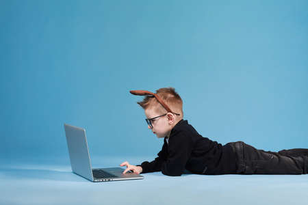 Portrait of casually dressed little boy leaning on white pillow, while hugging it, feeling tired after long full day, with cheerful smile, having rest.の写真素材