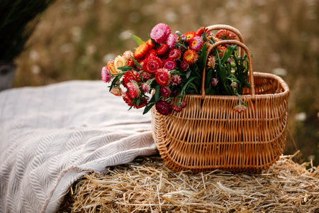 straw basket with flowers on a straw stack covered with a linen tablecloth outdoors on summer suny...
