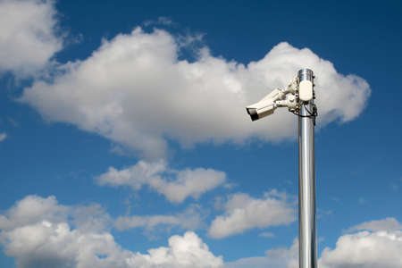 Outdoor security cctv cameras on a pole with blue cloudy sky background.の写真素材