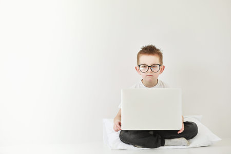 Smart child boy adjusts his glasses and having fun on the gray background, close-up. Studio juvenile...