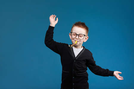 Smart child boy adjusts his glasses and having fun on the gray background, close-up. Studio juvenile portrait in casual clothes. copyspace.の写真素材