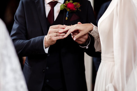 Hands of bride and groom in solemn process of exchanging rings, symbolizing the creation of new...