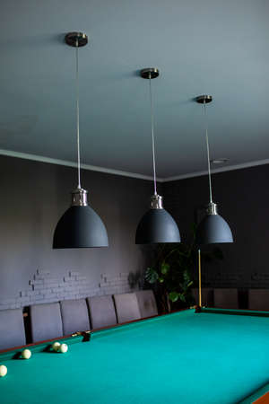 Close up of black stylish lamps hang over billiard table. Leisure activity interior design elementsの写真素材
