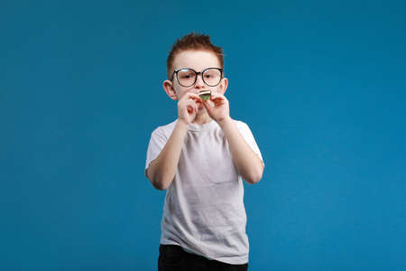 Adorable smiling child boy in glasses is lying in bed. morning dreaming on white bedの写真素材