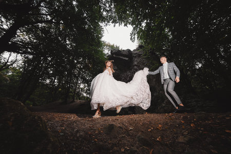 Wedding couple are walking in the forest. bride in long white dress and groom in suit.の写真素材