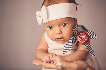 Happy woman mother holding a newborn cute baby girl in her arms at home. Mom with a child in her hands.の写真素材