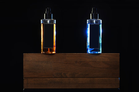 two bottles with yellow and blue liquid. two spray spraying cans on black background on wooden...