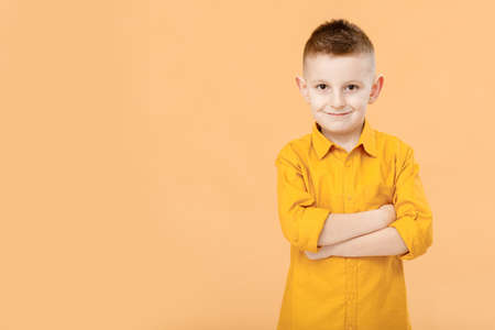 Photo of attractive cheerful nice school boy standing with his arms crossed in front of camera while isolated on yellow background. High quality photo.の写真素材