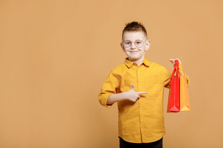 Portrait of funny clever school boy with headphones in yellow shirt. yellow studio background....