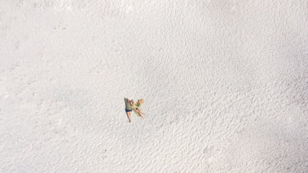 Young couple enjoying food and drinks in beautiful summer green park on romantic date picnic, handsome man and woman with curly hair are hugging outdoors.の写真素材