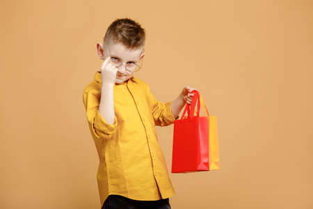 Portrait of funny clever school boy with headphones in yellow shirt. yellow studio background. Education. Looking, smiling and showing a thumb up at the camera. High quality photo.の写真素材