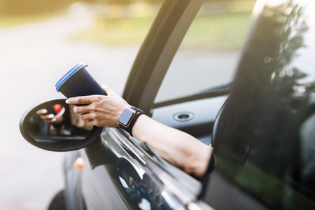 Man hand holding white paper cup of hot coffee in a car. coffee in the car