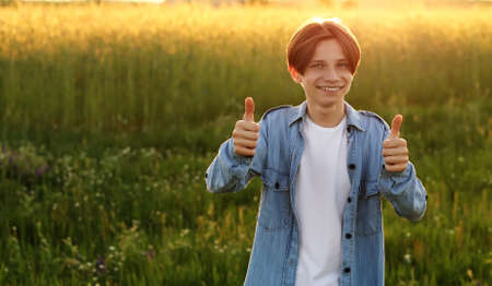 Handsome young man with stylish haircut. Portrait of teen boy with youth hairstyle is standing on gray backgroundの写真素材