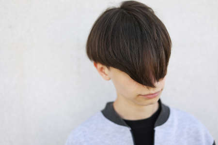 Handsome young man with stylish haircut. Portrait of teen boy with youth hairstyle is standing on gray backgroundの写真素材