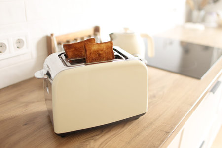 Toasted bread and toaster for breakfast. Modern white toaster and roasted bread slices toasts inside...