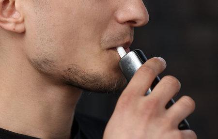 close up of a man with an electronic cigarette. man smokes an electronic cigarette in a natural...