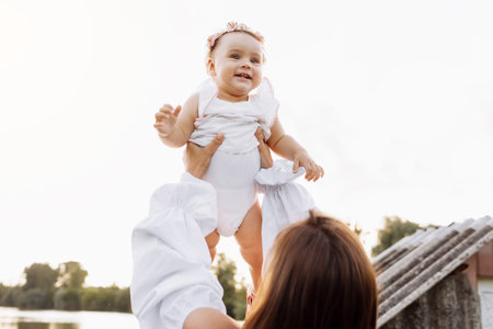 mother throws baby in nature, girl flies in the sky. Portrait mom with child together. mommy, little...