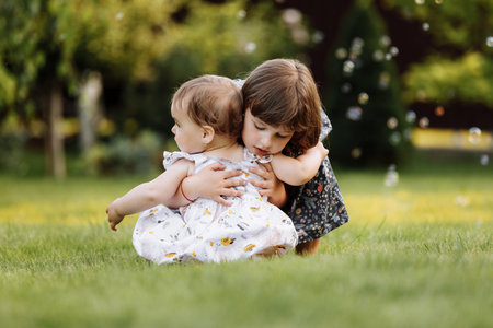 two little child girls are hugging outdoors in nature on summer sunny day. Little girlfriends in the park. Children Friendship Together Smiling Happiness Conceptの写真素材
