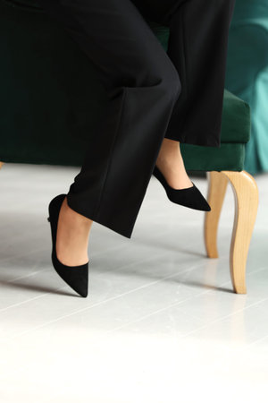 Cropped photo of legs in a classic black high heels shoes and black pants of a business woman...