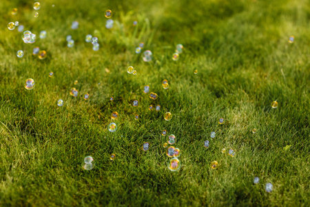 bright soap bubbles on summer natural green abstract background. many flying soap bubbles in sunny...