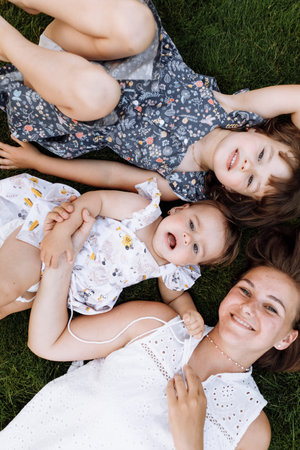 Family day, mother's day. Beautiful smiling young mom and two child daughters cuddling happy...