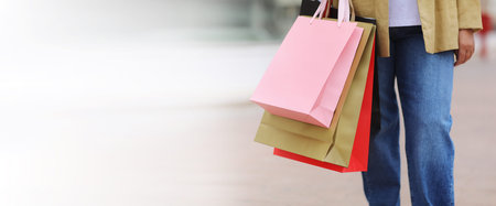 Black Friday. Banner of cropped womans legs with colorful shopping bags on urban shopping mall...