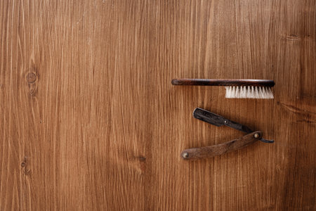 Vintage straight razor with wooden handle and brush isolated on wooden background. Professional barbershop tools. Place for text.の写真素材